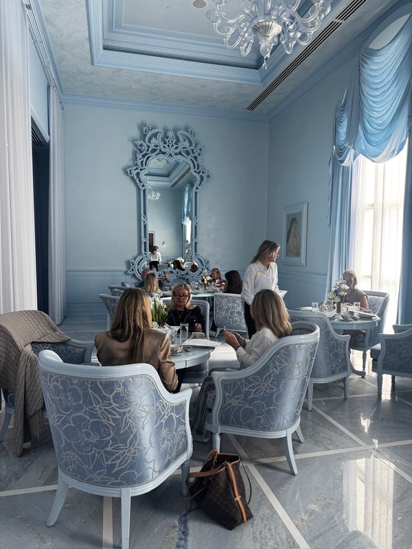 Guests at afternoon tea in the Bleu Room, a pale-blue salon with a chandelier and a tall mirror