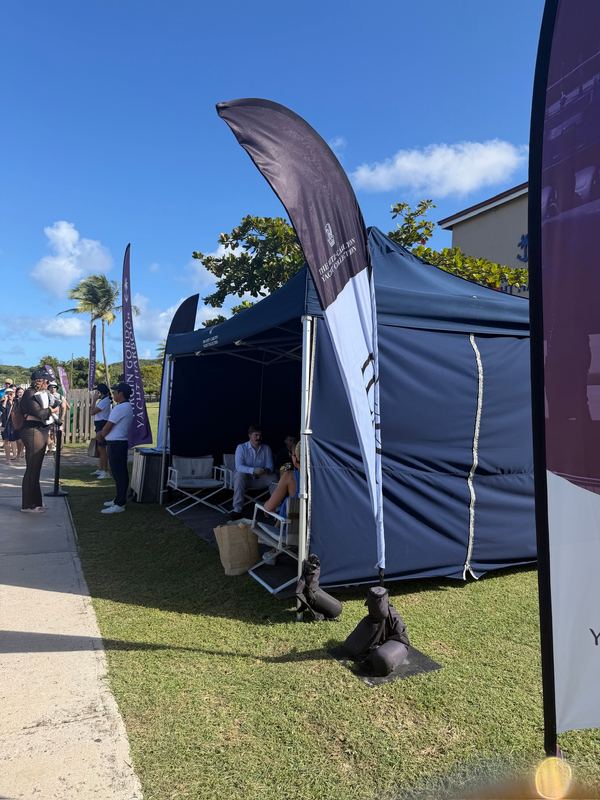 A navy Ritz-Carlton Yacht Collection tent with chairs in the shade at the tender landing on Virgin Gorda, guests waiting beside it
