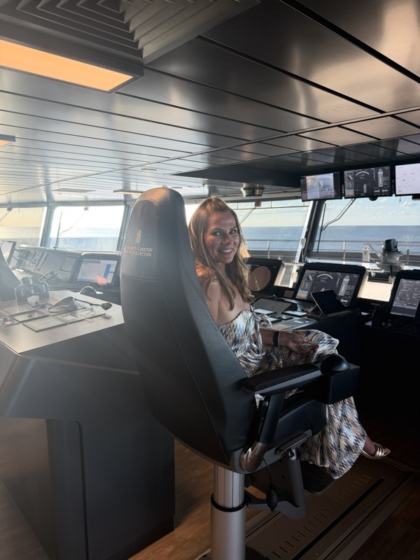 Jeannie at the bridge console looking out to sea, the crest embossed on the chair's headrest