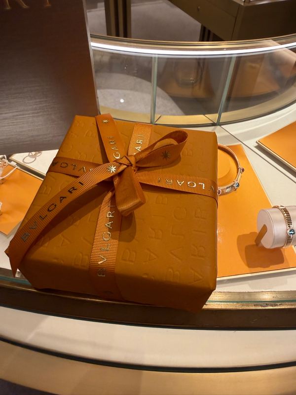 An orange Bvlgari box tied with ribbon on the boutique counter, jewellery in the case beside it