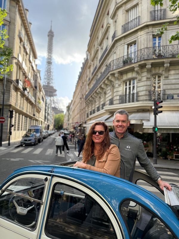 Christina and Colin in a 2CV on the Rue Saint-Dominique, the Eiffel Tower at the end of the street
