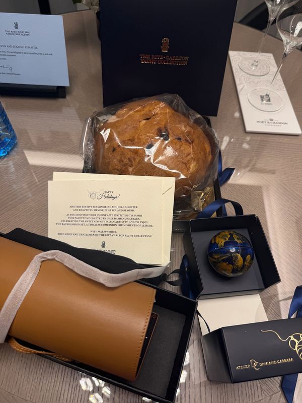 A panettone, a chocolate Christmas ornament, a leather travel backgammon set and a holiday card on the table in the suite