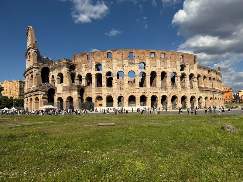 The Colosseum from the lawn on its west side, under a sky of broken cloud