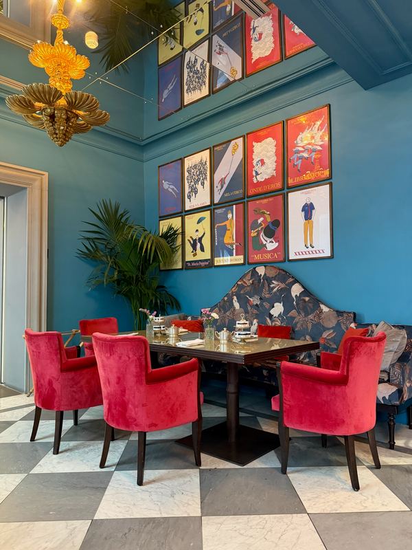 A dining room in Florence: blue walls, red velvet chairs, framed prints