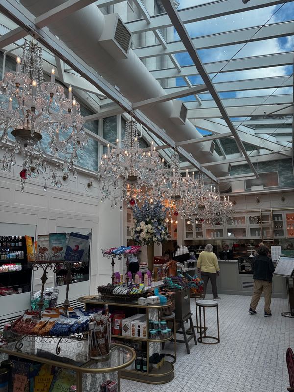 The Patisserie under a glass roof, crystal chandeliers hanging from the girders