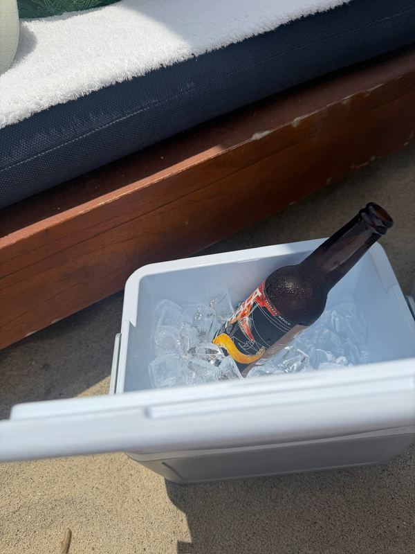 A beer on ice in the cooler beside the beach chair