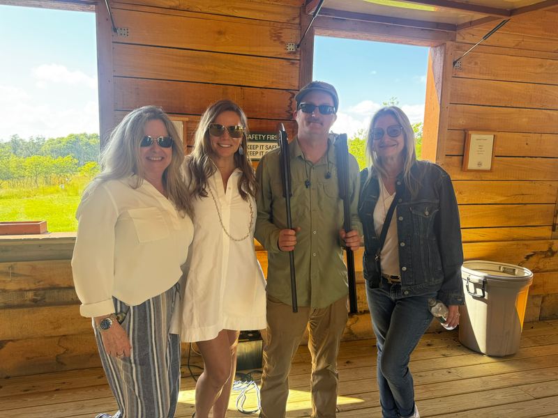 The Harvell Travel group — three women and the instructor holding a shotgun — inside the wooden shooting stand at the Field Club