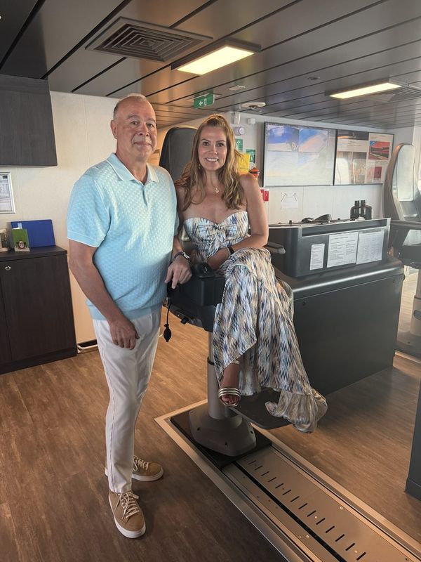 Steve standing beside Jeannie in the bridge chair, screens and consoles behind them