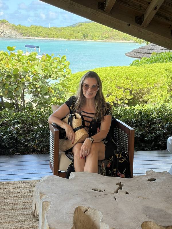 Jeannie seated under a timber pavilion above the turquoise bay at Little Dix Bay