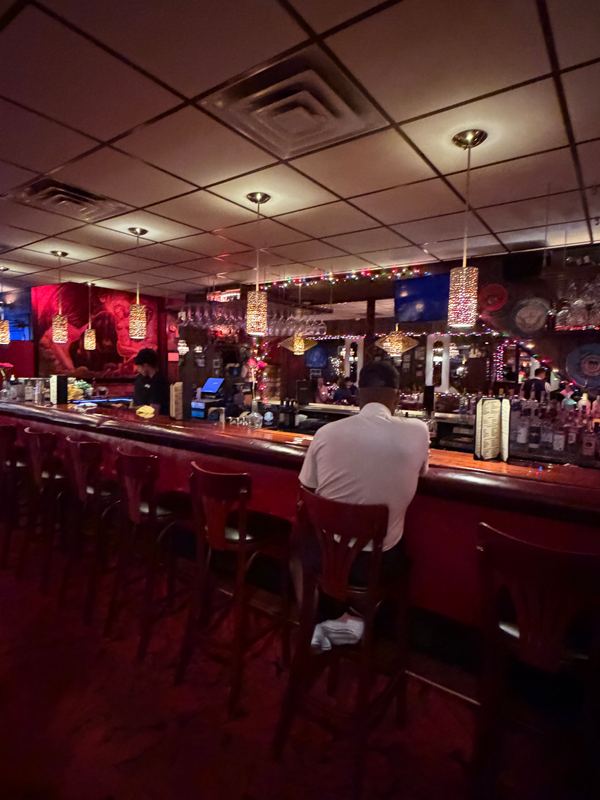 The red-lit bar at Five O&rsquo;Clock Steakhouse, a few stools taken