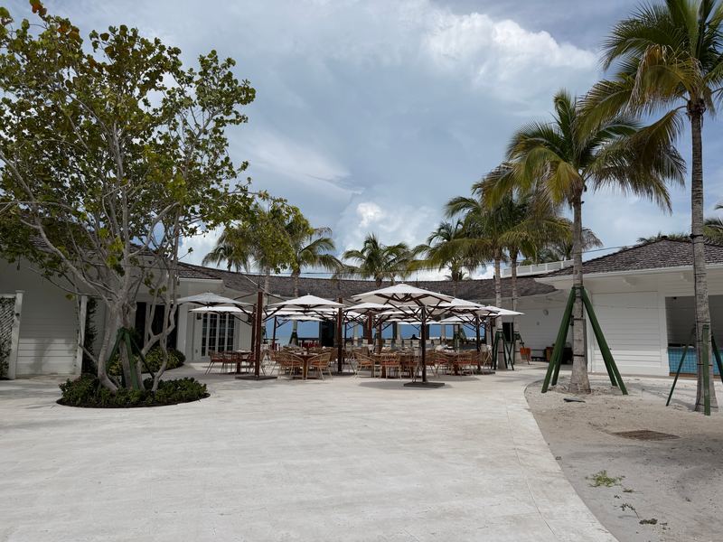 The beach club courtyard at Naples Beach Club, umbrellas under the palms