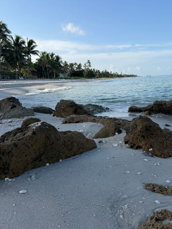 Rocks on the sand at the water's edge, the beach running north