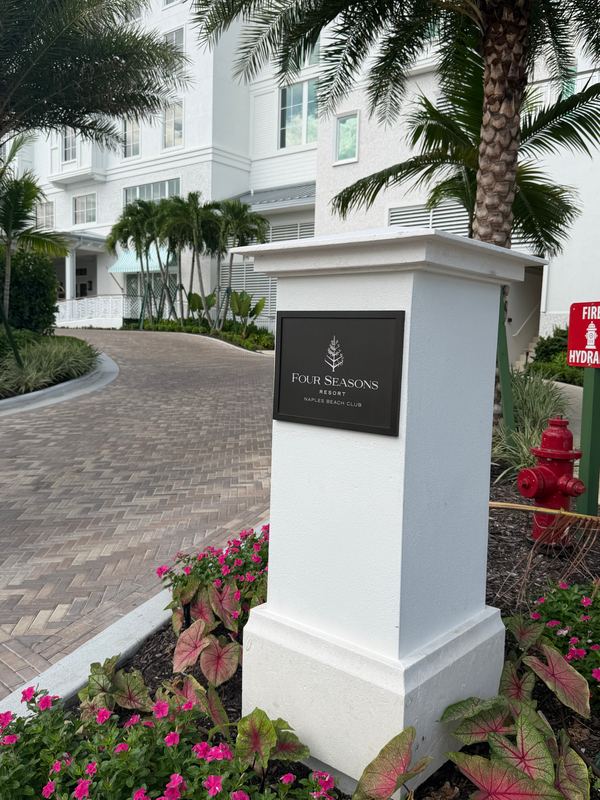The Four Seasons sign at the drive, palms and caladiums around it