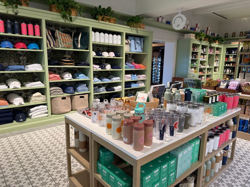 The store at Naples Trading Company: green shelves and hats