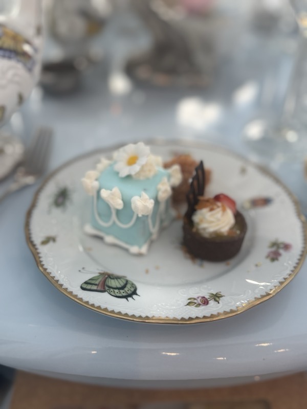 Two petit fours, one pale blue with a daisy, on a painted porcelain plate