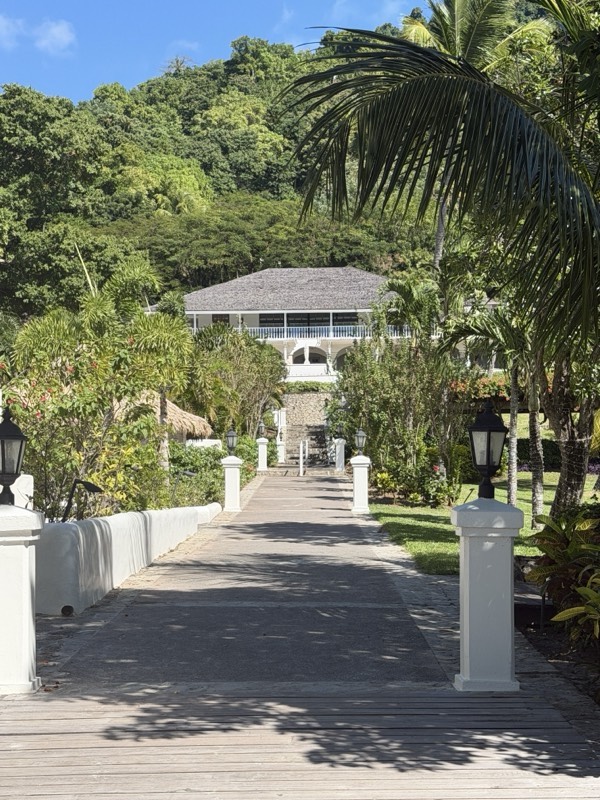 A timber walkway between planted beds to a white beach pavilion at Sugar Beach