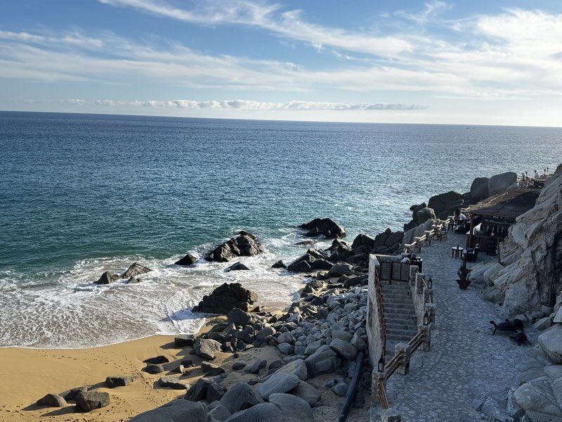 Rocky cove with golden sand and surf breaking over boulders