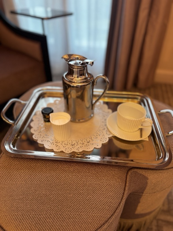 A silver coffee pot and cup on a silver tray in a hotel room
