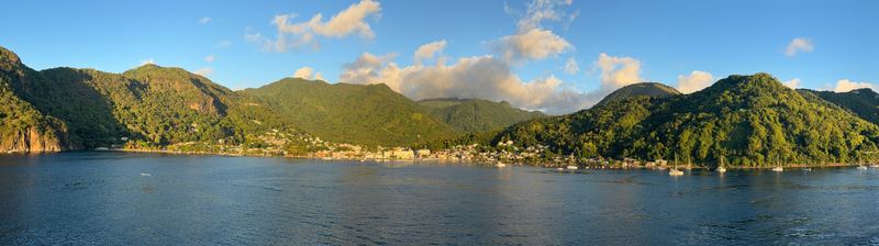 A panorama of Soufrière bay in late-afternoon light, the town between green headlands