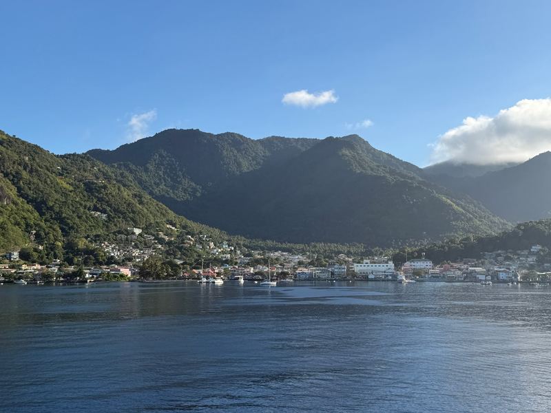 Soufrière town along the shore of its bay, green mountains rising behind, from the water