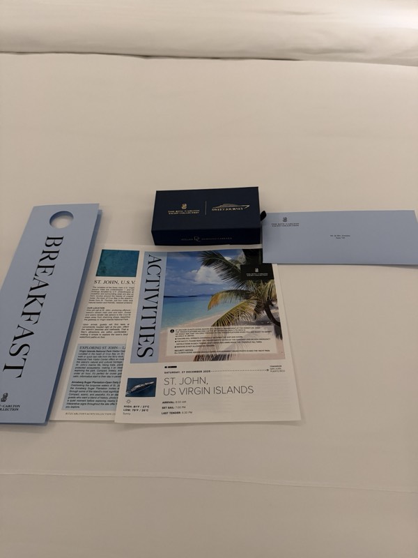 The breakfast door-hanger and the day's card for St. John, US Virgin Islands, left on the white bed linen at turndown
