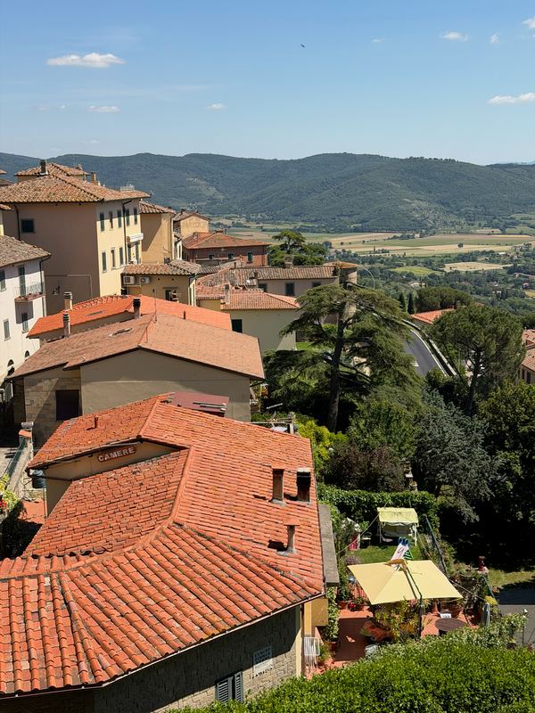 Terracotta roofs of a Tuscan hill town, the valley floor beyond