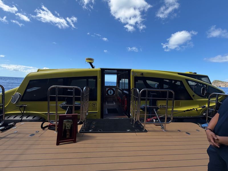 The ship's yellow tender alongside a wooden dock, its doors open