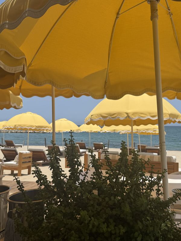 Scalloped yellow beach-club umbrellas layered over loungers and the sea